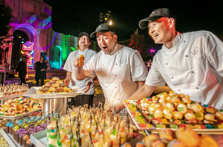 Wolfgang Puck Catering chefs smiling behind a display of desserts